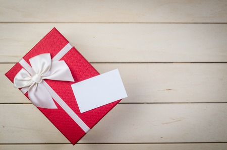gift box with white bow and blank name card on wooden board backgroundの写真素材