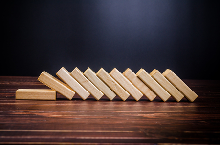 domino effect made up from wooden blocks shape toy on wooden board background,domino effect in business conceptの写真素材