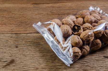 walnuts in plastic bag package on wooden tableの写真素材