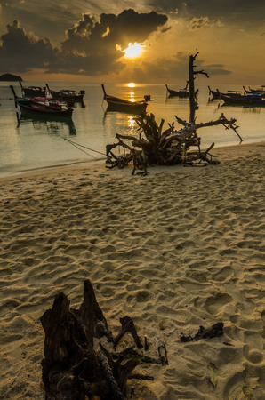 sunrise beach with stump foreground and long tail boat at the south of Thailand ,Lipe island ,Thailandの写真素材