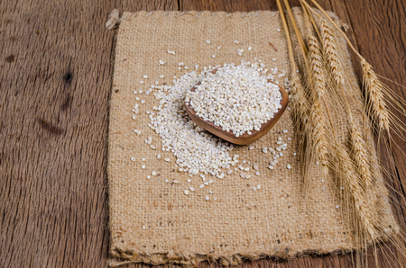Pearl barley in wooden bowl on sackcloth,Barley grain is raw material of bread, beer, whiskeys, vodkas,agriculture productの写真素材