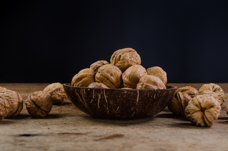 Heap of walnuts in coconut shell on wooden tableの写真素材
