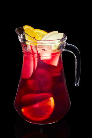 Cherry, apple and orange cold lemonade in pitcher isolated on black backgroundの写真素材