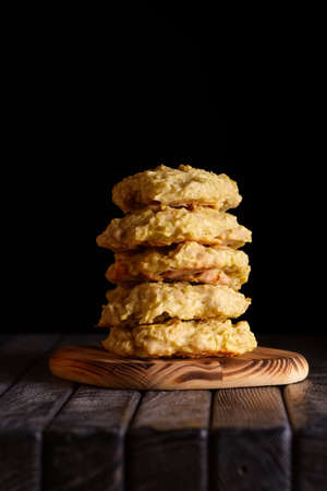Low key photo of  stack of of ginger, lemon and apple biscuits on wooden table. Chocolate chip cookies on dark wooden background with copy space.の写真素材