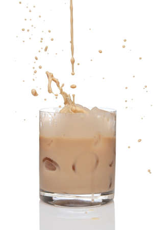 Irish creme liqueur pouring in a glass full of ice.の写真素材