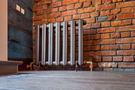 Vintage heating radiator for home with legs. Old cast iron central heating battery.の素材 [FY310125462785]