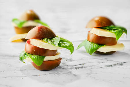 Brown chocolate tomato, mozzarella and basil cutted on slices and stacked on marble background (selective focus photo)の写真素材