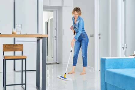 Young woman cleaning her flat with mopの写真素材
