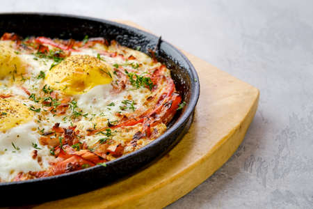 Closeup view of eggs with bell pepper and tomato baked in oven in cast-iron skilletの写真素材