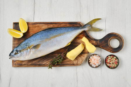 Top view of whole fresh chinook on wooden cutting board with spice, lemon and gingerの写真素材