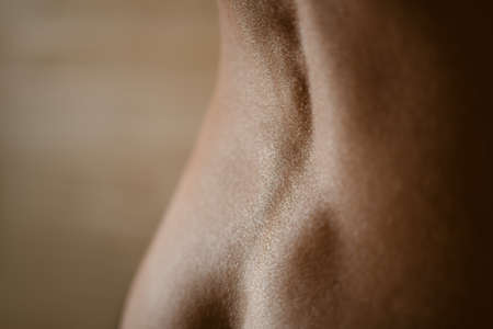 Closeup photo of bare female lower back (photo taken at wide open aperture with extreme shallow depth of field)の写真素材