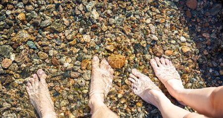 Male and female feet in shallow waterの写真素材