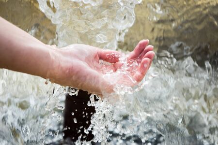 Caucasian woman holding palm in cold splashing waterの写真素材