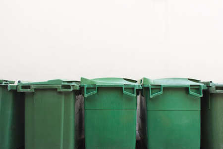 Green city trash cans on white wall
