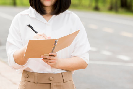 Close-up of woman standing writing in a notebook of education conceptの写真素材