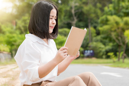 Asian woman sitting and holding a book to read vacation conceptの写真素材