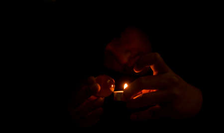 A mysterious man in black is performing a ritual, using candles and crystal balls for superstitions.
