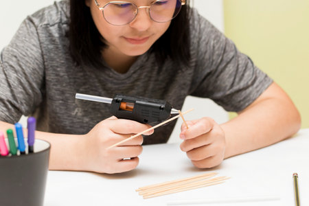 Close-up woman using a glue gun to create inventive ideasの写真素材