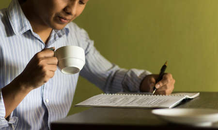 Asian men are working and writing notes on notebooks and coffee on a relaxed work day.