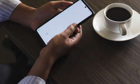 Close-up of business man holding a smartphone to use technology to communicate about workの写真素材