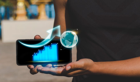 Hand holding smart phone with growth graph and earth globe on screen.
