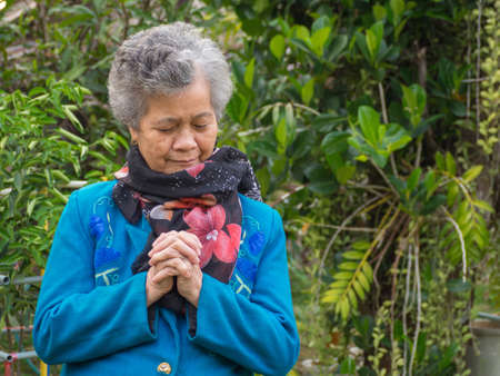 Closeup portrait outdoors of an elderly woman with eyes closed praying.の写真素材