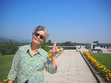 Portrait of a elderly woman standing and wearing sunglasses against a nature background.の写真素材