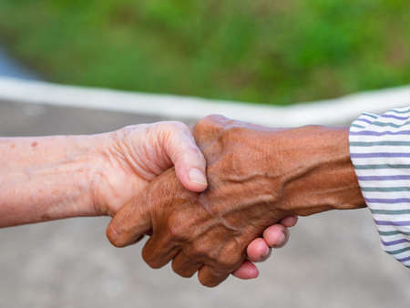 Close-up image of shaking hands between elderly womans. Unity Concept.の写真素材