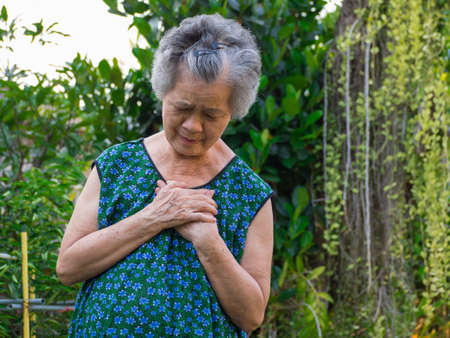 Elderly woman having a heart attack and grabbing her chest.