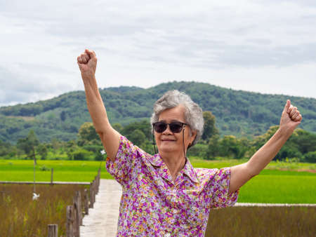 Portrait of happy senior woman raising both arms upwards.の写真素材