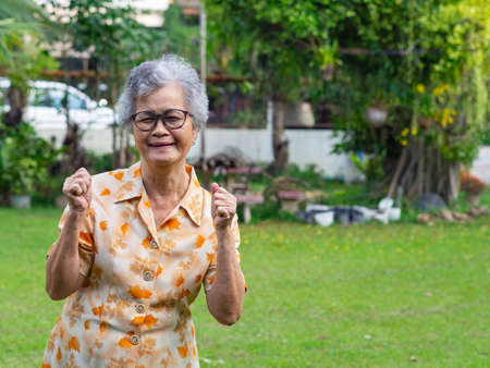 Portrait of happy senior woman clenching fists. Excited for success with arms raised celebrating victory smiling.の写真素材
