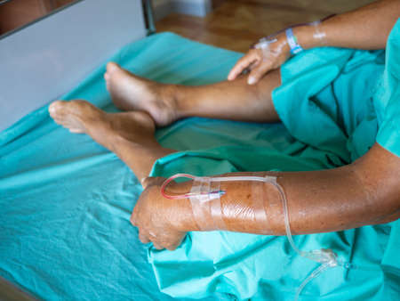 Close-up of senior asian man patient is receiving blood solution on bed in the hospital.