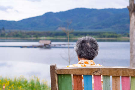 Senior woman sitting back side the lake.の写真素材