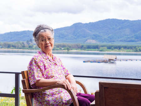 Portrait of elderly woman sitting side the lake.の写真素材