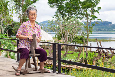 Elderly woman sitting on wooden rocking horse.の写真素材