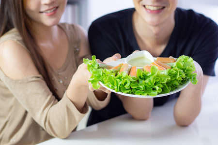 Close-up of hands young couple holding a dish of fresh vegetables  nutritious at kitchen.  Foods for diet, low calories. Eat vegetables organic for good healthy. Health foods conceptの写真素材