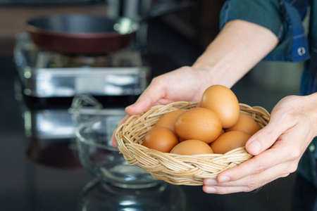 Close-up photo of the young man's hands holding a basket full of eggs organic in kitchen to prepare food. Eggs are beneficial to the body. Protein helps the body healthy. Health foods conceptの写真素材