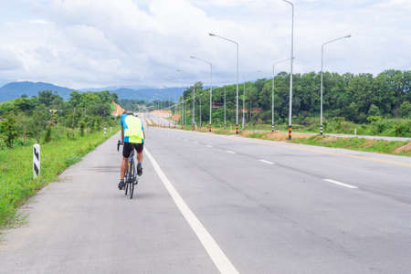 Back view of young man cyclist training on a road