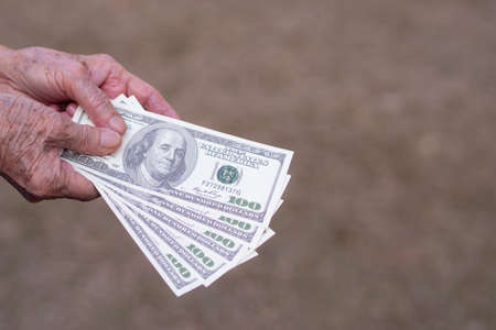 Close-up of elderly woman hands holding $100 amount of $500 dollars. Selective focus. Space for textの写真素材