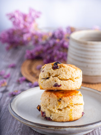 Close-up of traditional British scones on a plate with a tea cup and flower blurred background. Space for text.の写真素材
