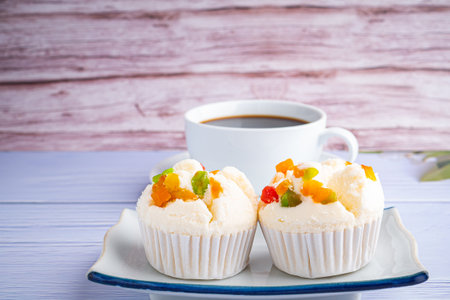 Side view of Thai steamed cupcakes topped with dry fruit on plate on blue cloth with a white coffee...