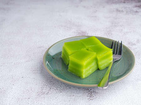 Layer sweet cake (or khanom Chan) and small fork on a plate on gray stone background. Space for text. Thai dessert. Selective focus. Relax time. Concept of dessertの写真素材