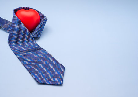 Happy Father's Day with a blue tie, red heart, and a gift box laid isolated on a light blue background with space for text. Side view.の写真素材