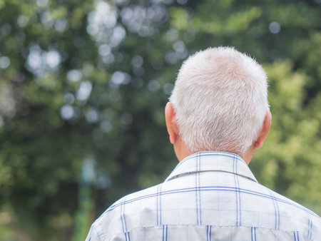 Back view of an elderly man with short gray hair while standing outdoors. Space for text. Aged people and relaxation concept.の写真素材