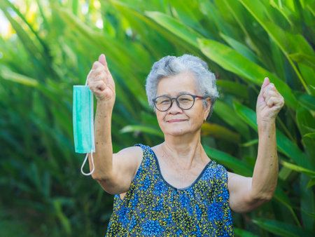 The end of COVID 19 pandemic. End lockdown back to Normal life. Senior woman hand holds a medical mask in her hand. Victory hand mask. A symbol of the end of pandemic Coronavirus disease.の写真素材