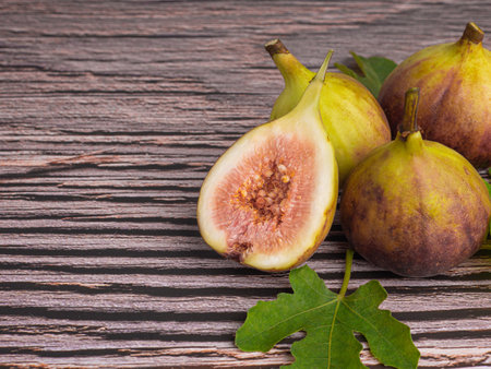 Figs fruit with green leaves placed on the old wooden table in the kitchen. Space for text. High Vitamins fruit. Close-up photo. Healthy fruits and healthcare concept.の写真素材