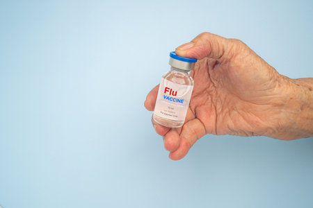 Close-up of hand a senior woman holding and flu vaccine for injection. Influenza vaccine for...