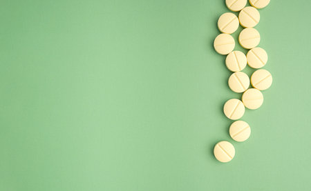 Pile of light yellow tablets medicine for people's health to heal diseases isolated on a green...