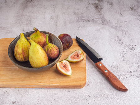 Ripe figs and knives isolated on a wooden cutting board on a cement floor with space for text. High Vitamins fruit. Concept of fruits healthy.の写真素材