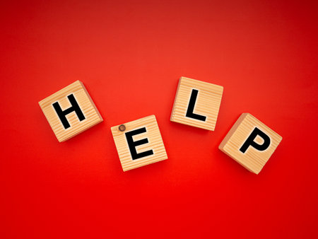 HELP word is written on wood blocks isolated on a red background. Top view. Close-up photo.の写真素材
